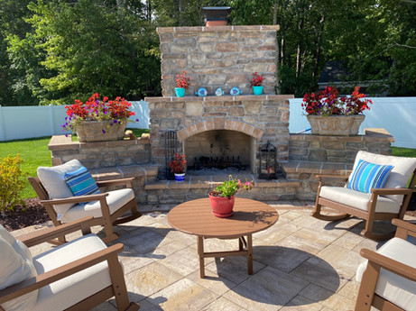 Scenic patio in Lewes, DE, with a rustic stone fireplace and seating, perfect for outdoor gatherings